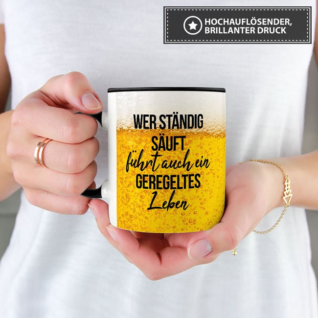 Bier Tasse mit Spruch - Wer st&auml;ndig s&auml;uft f&uuml;hrt auch ein geregeltes Leben - Innen &amp; Henkel Schwarz